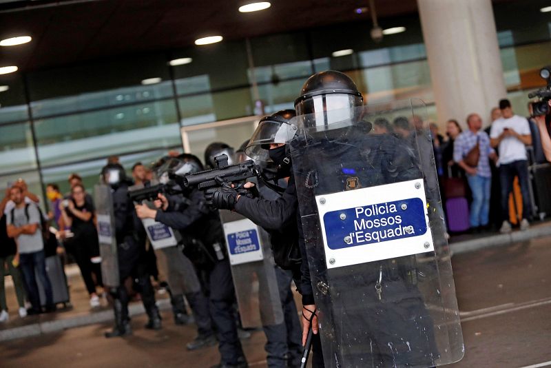 Miembros de la Policia Nacional controlan a las centenares de personas que se agolpan ante el Aeropuerto del Prat.