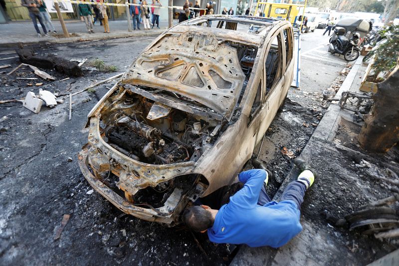 Un trabajador retira un coche quemado tras las protestas violentas de la pasada madrugada en las calles de Barcelona.