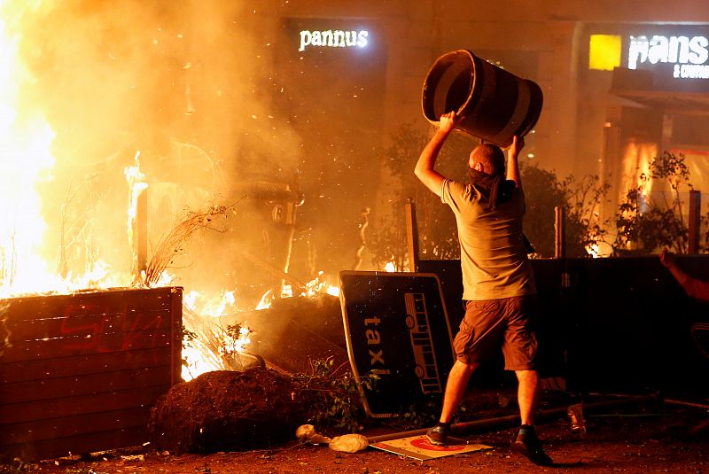 Un manifestante arroja un contenedor al fuego durante la Huelga general en contra de la sentencia del 'procés'.
