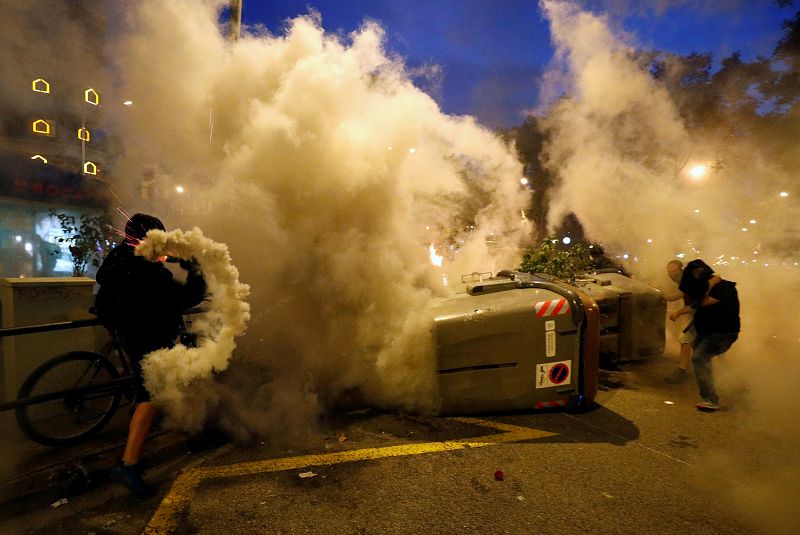Un manifestante arroja un bote de gas lacrimógeno a la Policía durante la Huelga general en Cataluña.