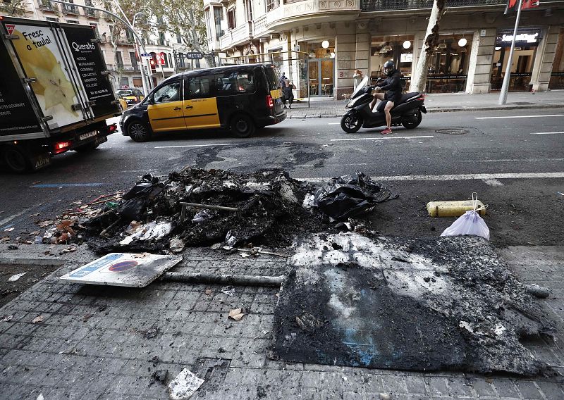 Aspecto que presenta este sábado las calles de Barcelona con restos de contenedores quemados tras los incidentes registrados anoche.