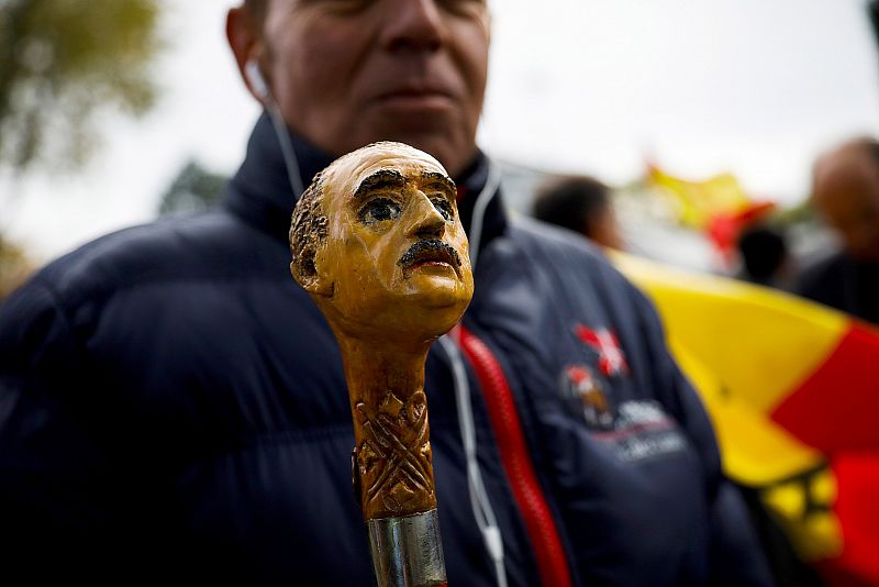 Un hombre porta un bastón decorado con la cabeza de Franco