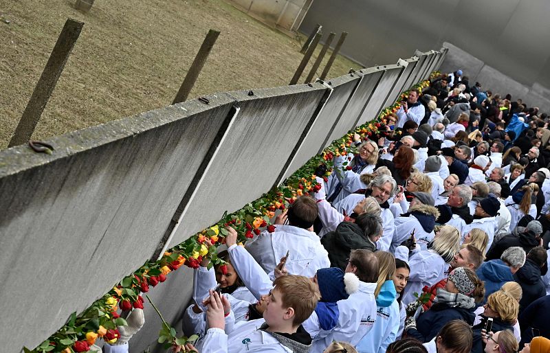 Los asistentes a la ceremonia que conmemora el treinta aniversario de la caída del Muro de Berlín colocan flores en el Memorial del Muro