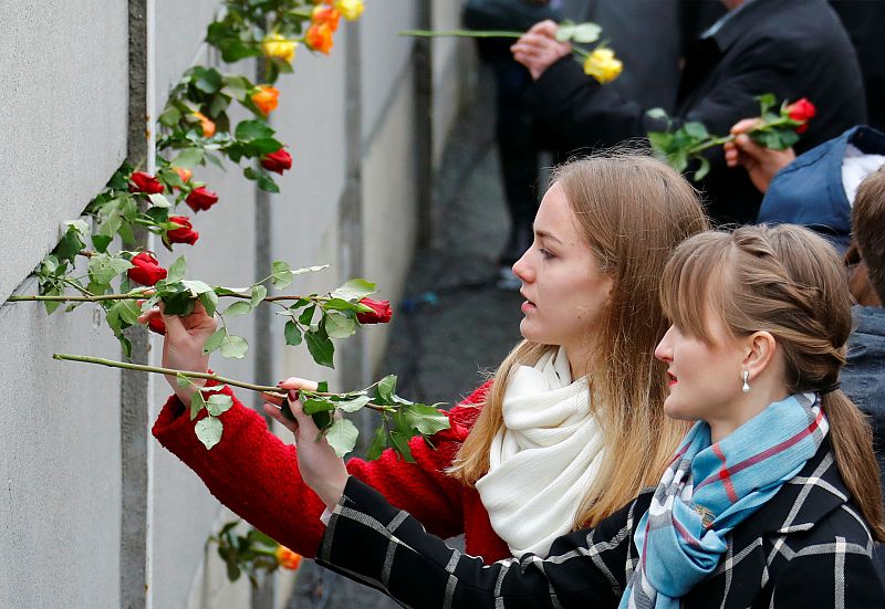 Asistentes a la ceremonia depositan flores en el memorial del Muro de Berlín.