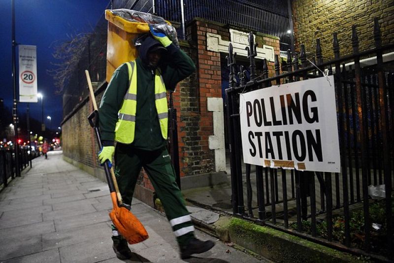 Un barrendero pasa por una mesa electoral durante las Elecciones generales en Londres. 