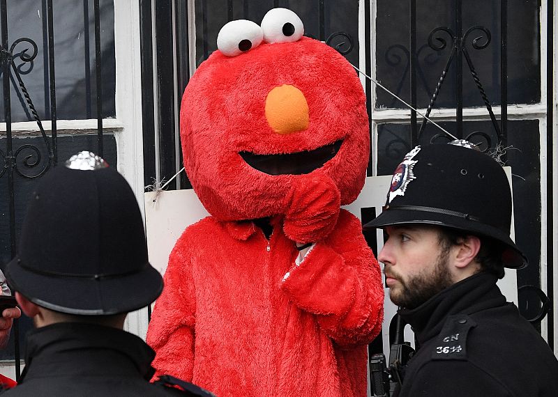 Dos policias junto a un manifestante disfrazado de 'Elmo' a las puertas de un colegio electoral.