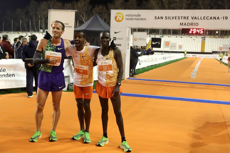 El belga-somalí Bashir Abdi (c) ganador de la carrera posa con el segundo clasificado, el ugandés Mande Bushendich (d) y el primer español Toni Abadía (i).