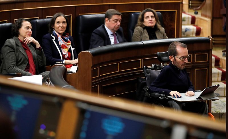 El diputado de Unidas Podemos, Pablo Echenique (d), sigue la intervención del candidato a presidente del Gobierno, Pedro Sánchez en el Congreso de los Diputados durante la primera jornada de su investidura como presidente del Gobierno.