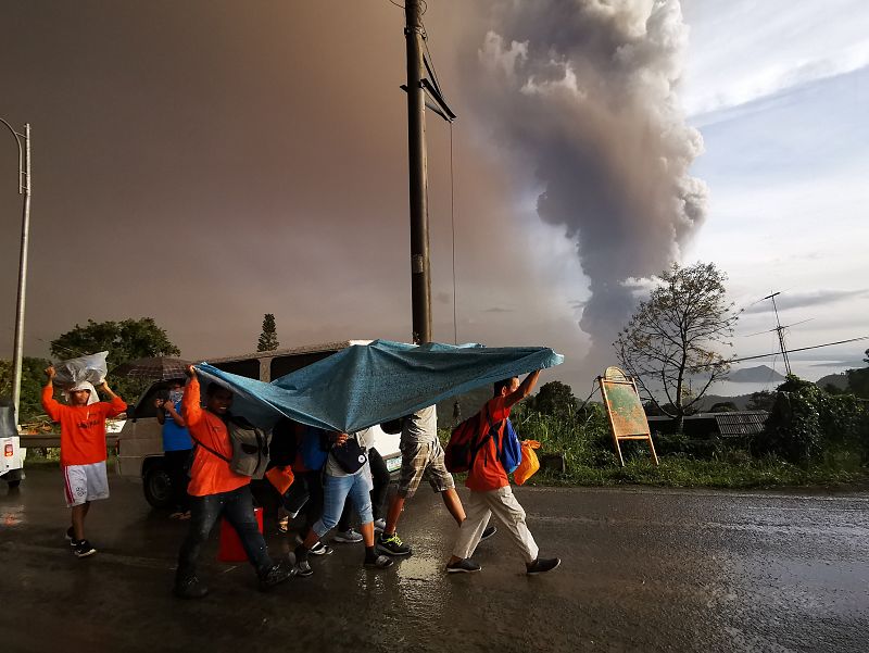 Varias personas se refugian bajo una lámina de plástico del volcán