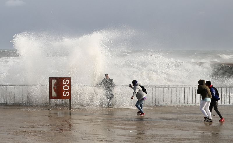 Turistas se toman fotos mientras las olas rompen por el temporal 'Gloria'