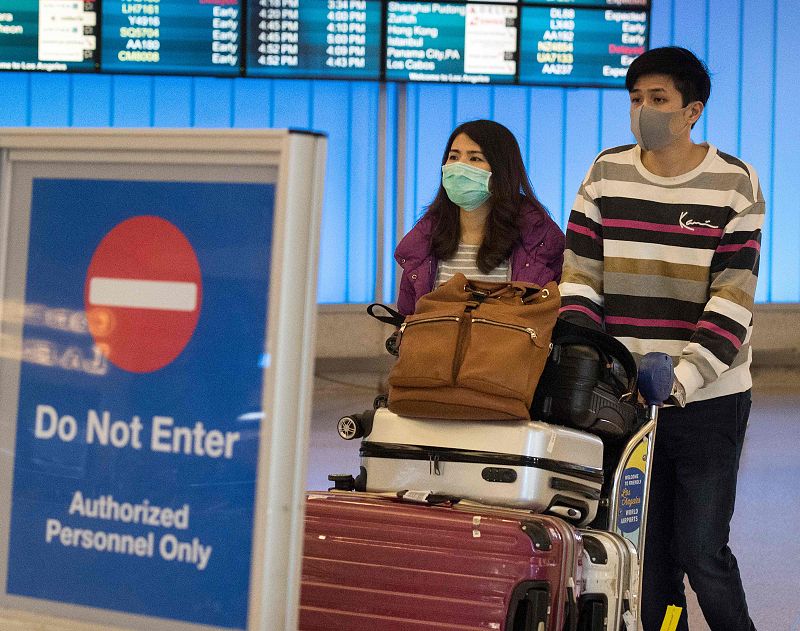 Pasajeros con mascarilla para protegerse contra la propagación del rotavirus a su llegada al aeropuerto internacional de Los Ángeles.