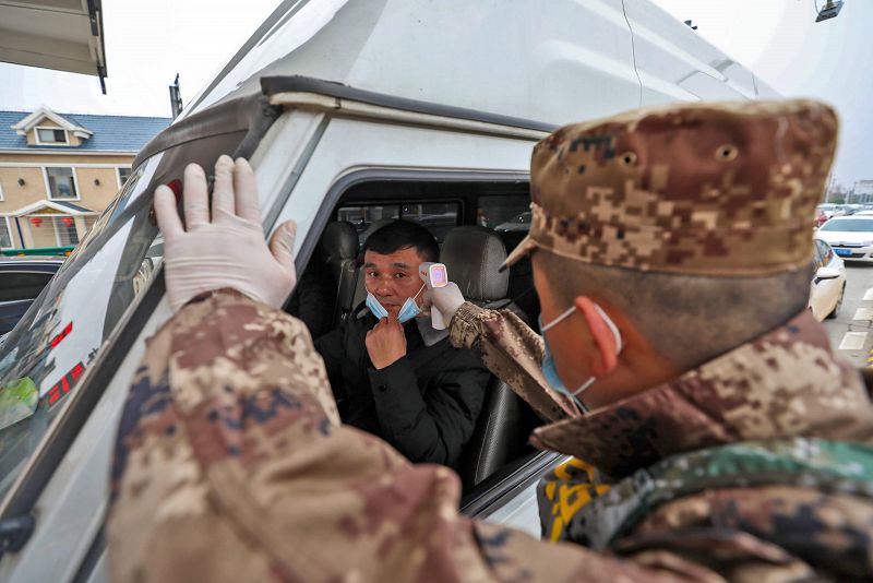 Un miembro del ejército toma la temperatura a un conductor en el peaje de una autovía en Wuhan.