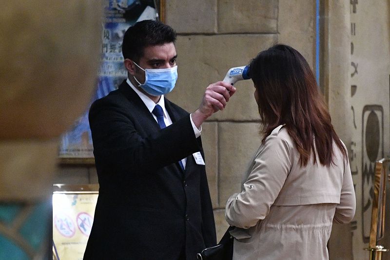 Un trabajador del hotel New Orient Landmark en Macao toma la temperatura a una huésped antes de su estancia.