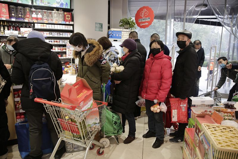 Residentes hacen colan en un supermercado a medida que los precios de algunos alimentos se disparan en Wuhan.