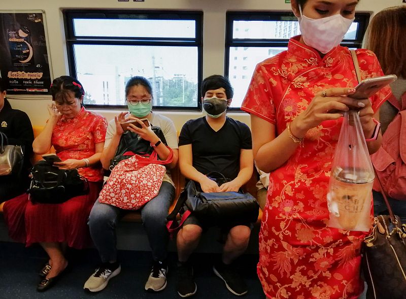 Una mujer vestida con traje típico lleva una mascarilla antes del año nuevo chino en un tren de Bangkok.