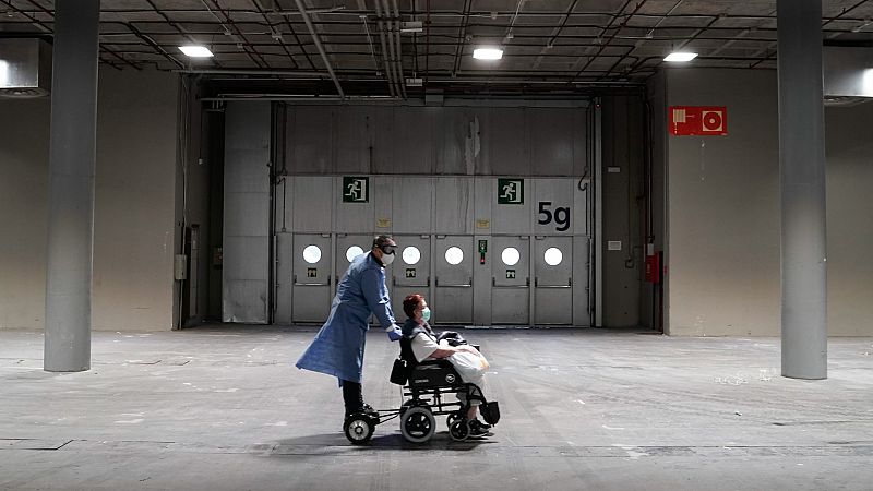 Un sanitario traslada a una paciente con coronavirus en el hospital de campaña instalado en el recinto ferial de Madrid.