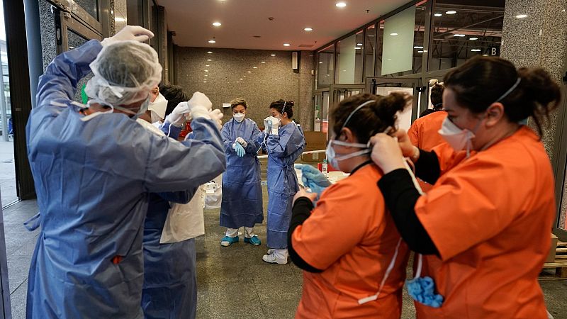 Sanitarios preparandose con monos y mascarillas de protección ante el virus en el hospital de Ifema.