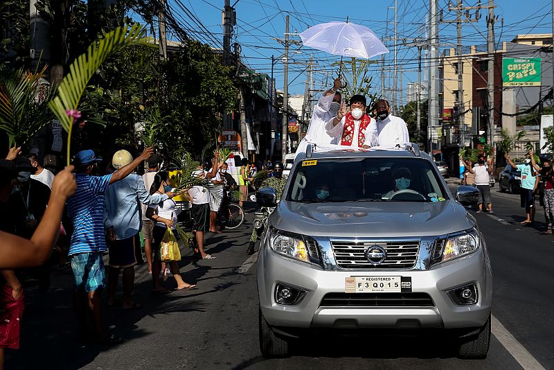 Un sacerdote católico reparte bendiciones desde un vehículo en las calles de Manila, Filipina