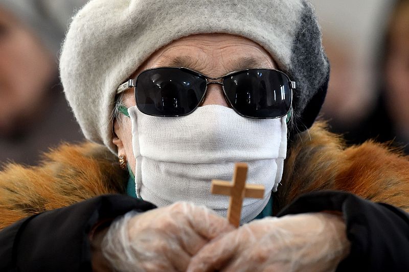 Una mujer con mascarilla porta una cruz en la ciudad bielorrusa de Ashmiany.