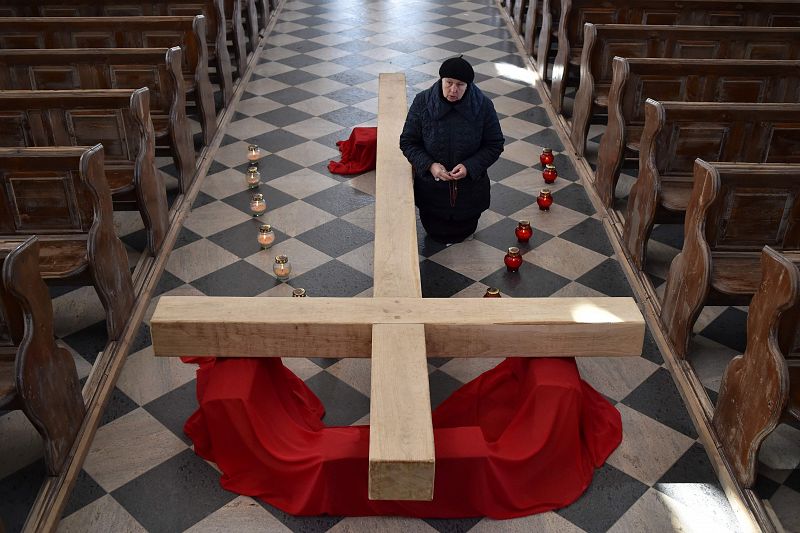 Una mujer se arrodilla ante una cruz en una iglesia vacía de Ashmiany, en Bielorrusia.