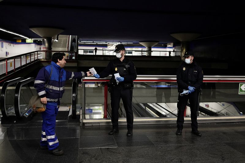 Los policías entregan mascaras faciales durante el confinamiento en una estación de metro.