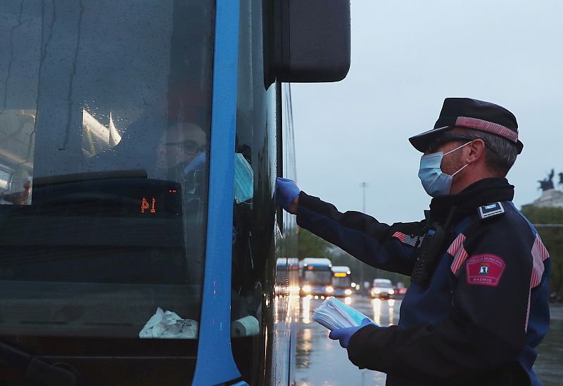 Un agente entrega mascarillas a un conductor de autobús en Madrid durante el confinamiento.