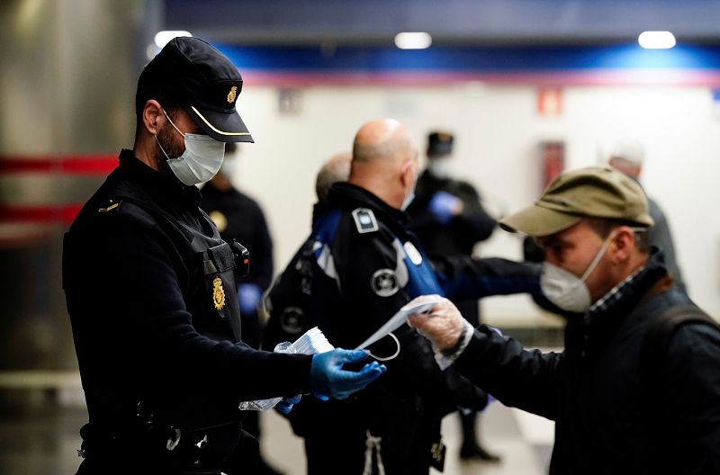 Un agente reparte mascarillas a los pasajeros en una estación de metro de Madrid.