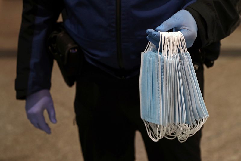 Un municipal sostiene mascara protectoras para repartirlas en la estación de Atocha de Madrid.