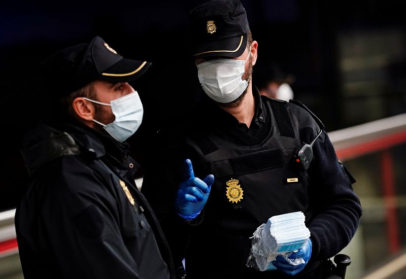 Dos policías reparten mascarillas en una estación de metro de Madrid durante el confinamiento.
