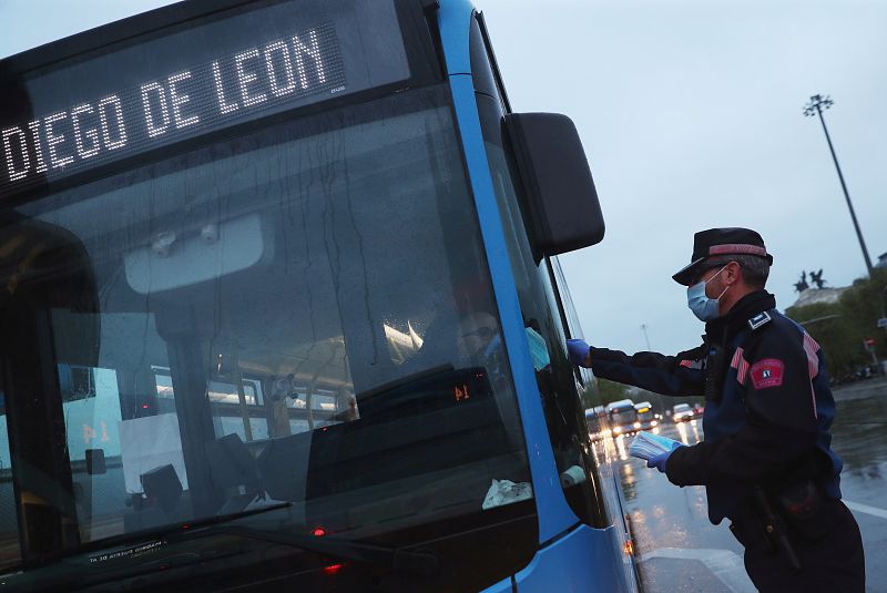 Un policía reparte una mascarilla a un conductor de autobús en Madrid.