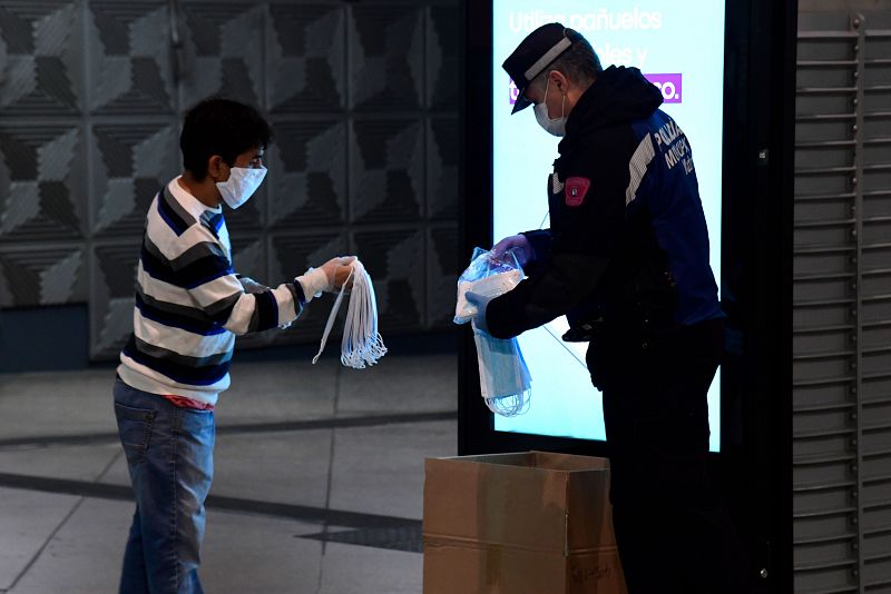 Un agente reparte mascarillas a los viajeros en la estación de Atocha de Madrid.