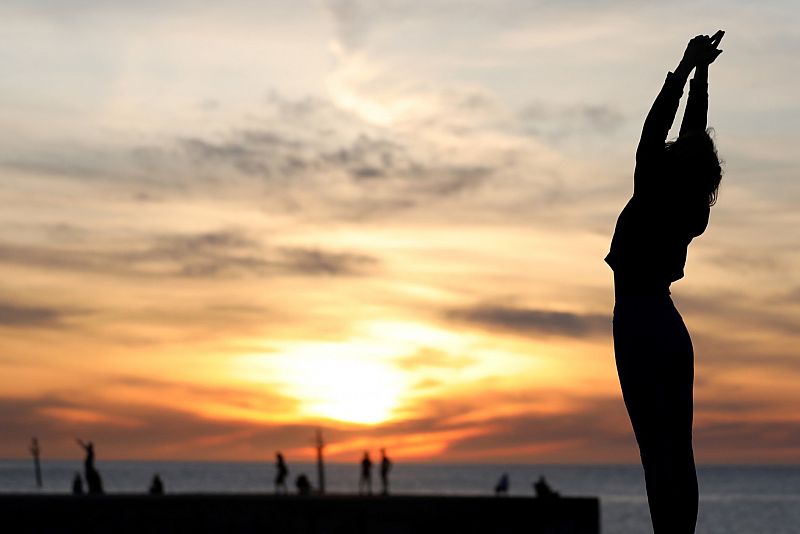 Una mujer hace deporte en la playa de la Barceloneta durante las horas que se permite el ejercicio individual al aire libre.