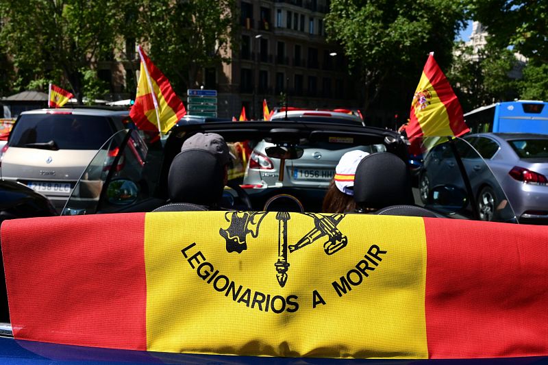 Manifestantes muestran una bandera en la que puede leerse el mensaje "Legionarios a morir", durante la manifestación promovida por Vox en contra del la gestión del Gobierno de la crisis del coronavirus.