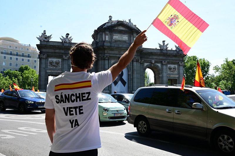 Un hombre eleva una bandera de España frente a la Puerta de Alcalá en Madrid.