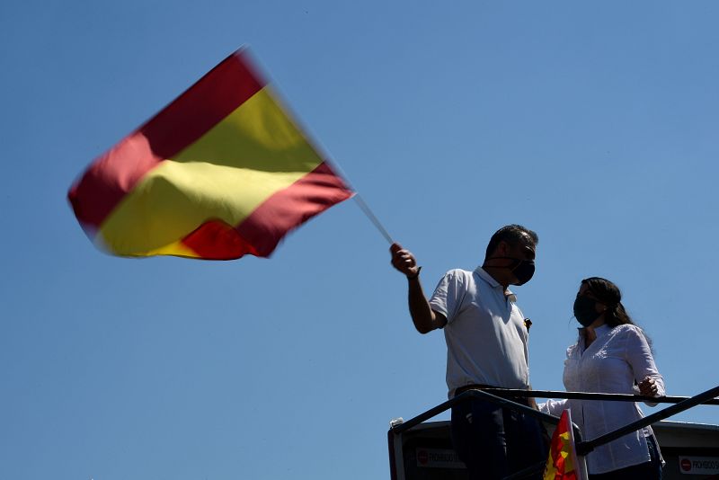 El secretario general de Vox, Javier Ortega Smith (i) alza una bandera de España en la Plaza de Colón de Madrid.