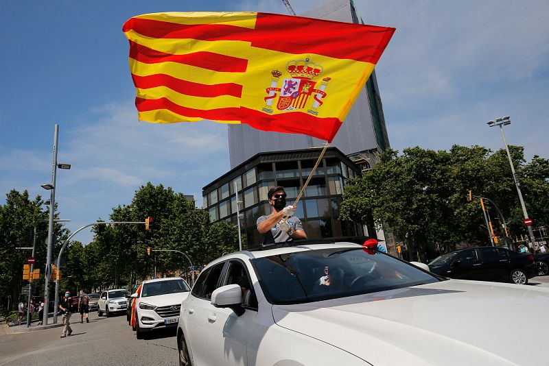 Un manifestante se desplaza en coche con una bandera de Cataluña y España.