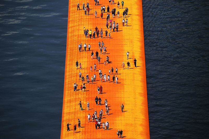 En esta foto de archivo tomada el 18 de junio de 2016, la gente camina sobre la monumental instalación titulada 'The Floating Piers' creada por el artista Christo Vladimirov Javacheff en el lago Iseo, en el norte de Italia.