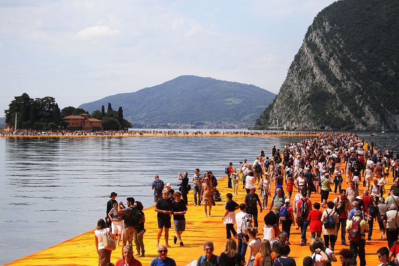 En esta foto de archivo tomada el 18 de junio de 2016, la gente camina sobre la monumental instalación titulada 'The Floating Piers' creada por el artista Christo Vladimirov Javacheff en el lago Iseo, en el norte de Italia.