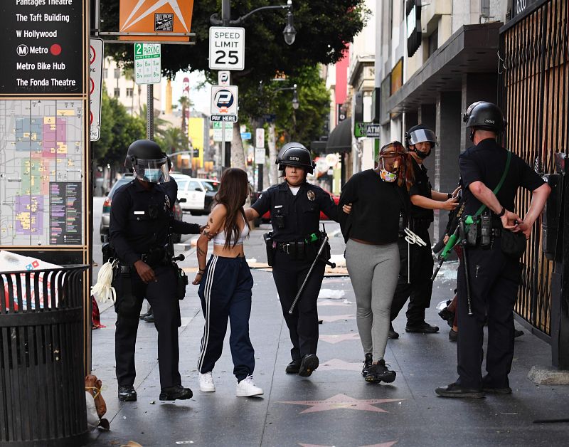 Unos agentes de policía arrestan a varias personas después de que una tienda fuera saqueada en Hollywood, California.