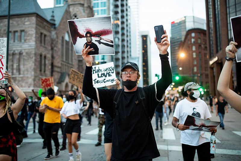 Un manifestante sostiene una foto y un teléfono durante una marcha por Brodway desde el Capitolio.