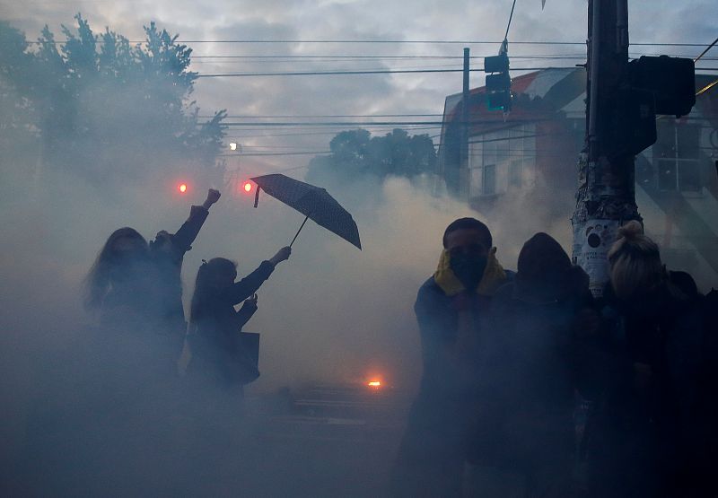 Un manifestante se protege de los gases lacrimógenos, gas pimienta y otros dispositivos de explosión repentina que lanza la policía.