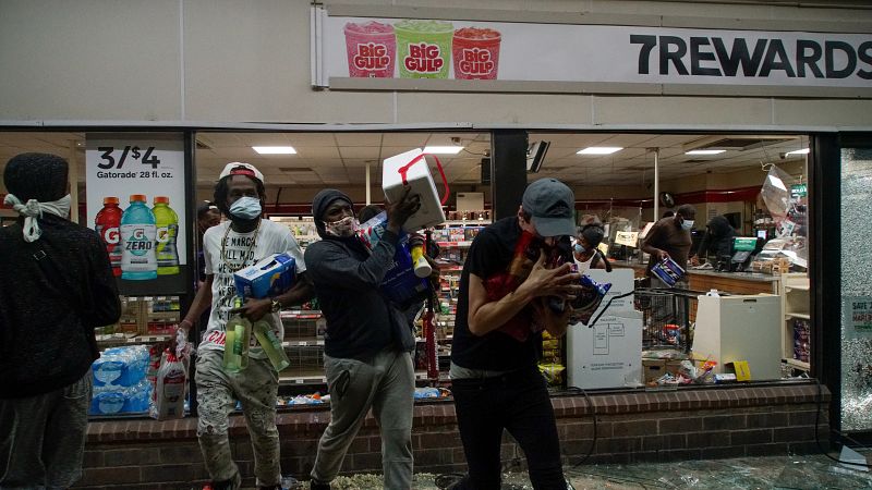 Los saqueadores salen por la ventana de un supermercado durante una protesta contra la muerte de George Floyd.