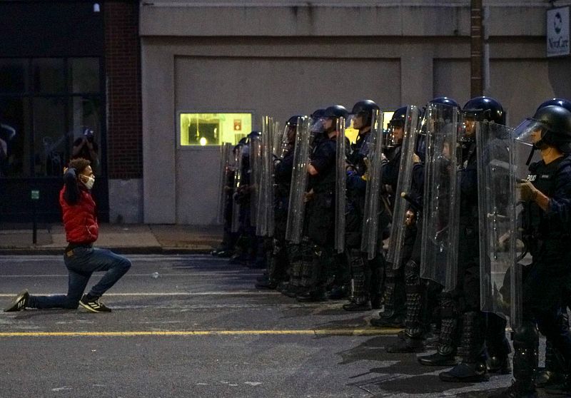 Un hombre se arrodilla frente a los agentes en protesta de la muerte del afroamericano George Floyd.