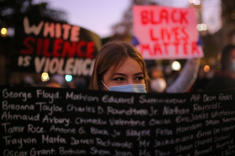 Manifestantes sujetan una pancarta en protesta por la muerte del hombre afroamericano a manos de un agente en Minneápolis.