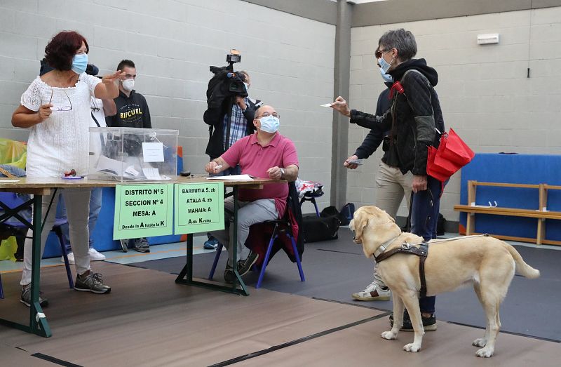 Una mujer invidente en el momento de votar en un colegio electoral en la localidad vizcaína de Durango, con todas las medidas de seguridad ante la pandemia del coronavirus.