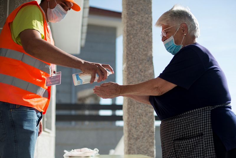 Una mujer se desinfecta las manos antes de votar en un colegio electoral de Requiás, Muiños (Ourense), este domingo con motivo de las elecciones autonómicas.