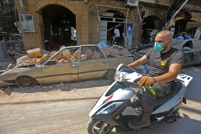 Un hombre con mascarilla conduce su motocicleta en el distrito comercial Gemmayzeh