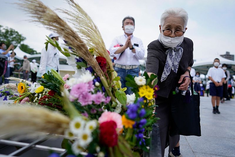 Una mujer ofrece una flor antes de rezar por las víctimas frente a un cenotafio en el Parque Conmemorativo de la Paz en Hiroshima.