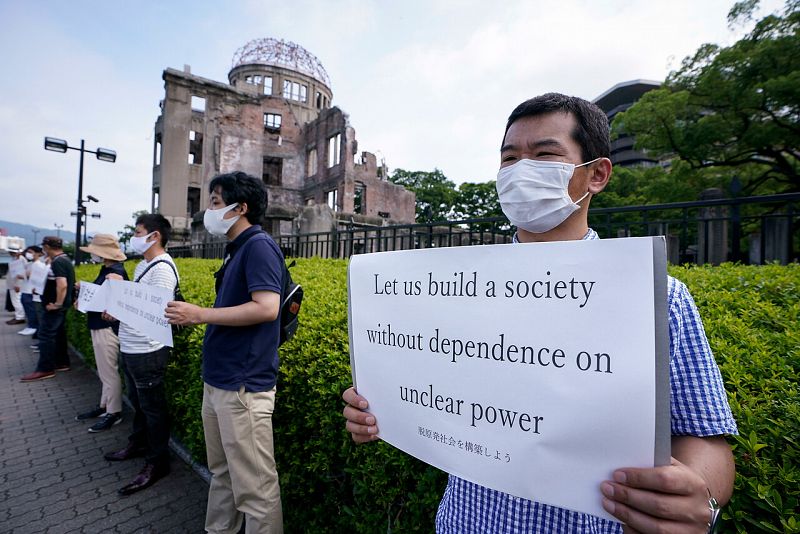 Un manifestante antinuclear sostiene un cartel frente a la Cúpula de la Bomba Atómica en la que pide construir una sociedad libre de de armas nucleares.