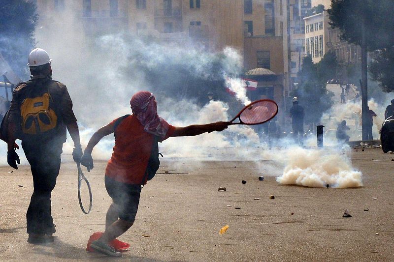 Un manifestante devuelve un bote de gas lacrimógeno con una raqueta de tenis